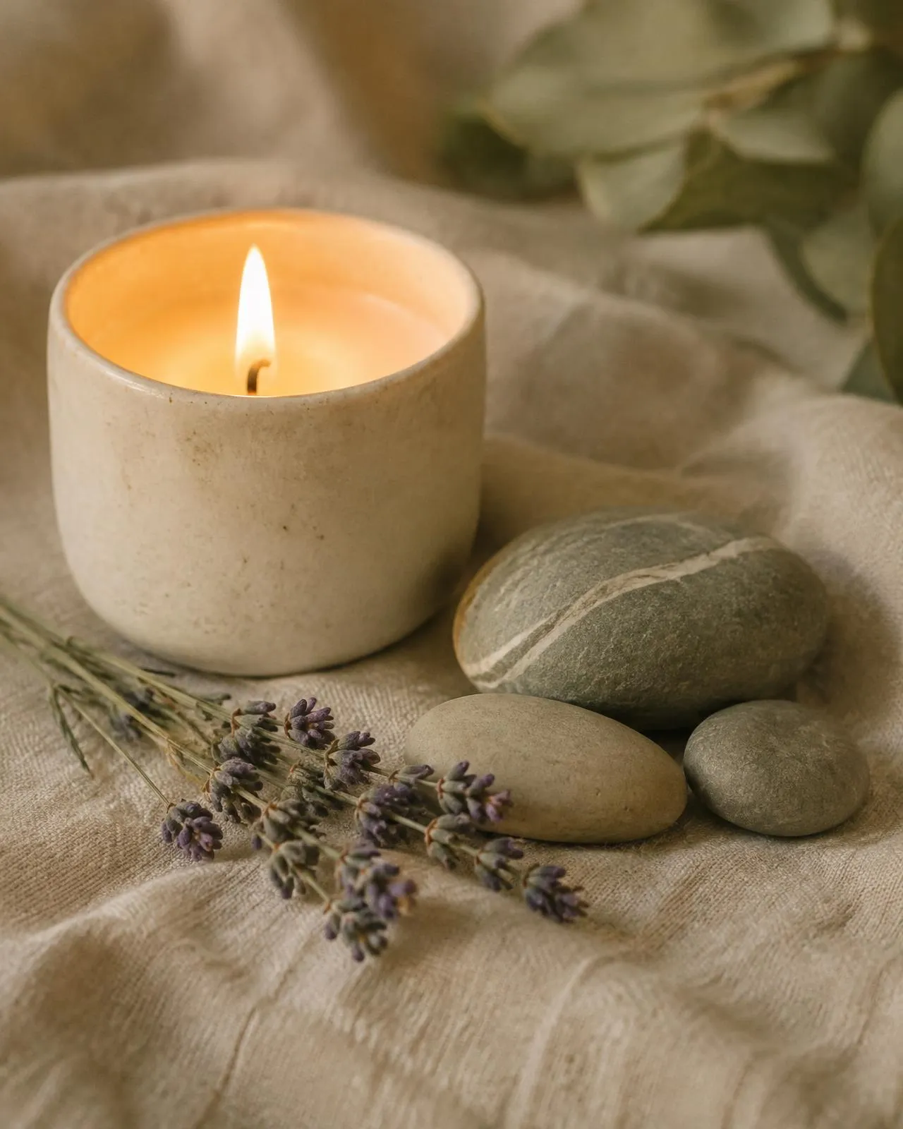 Lit candle, stones and lavender on linen